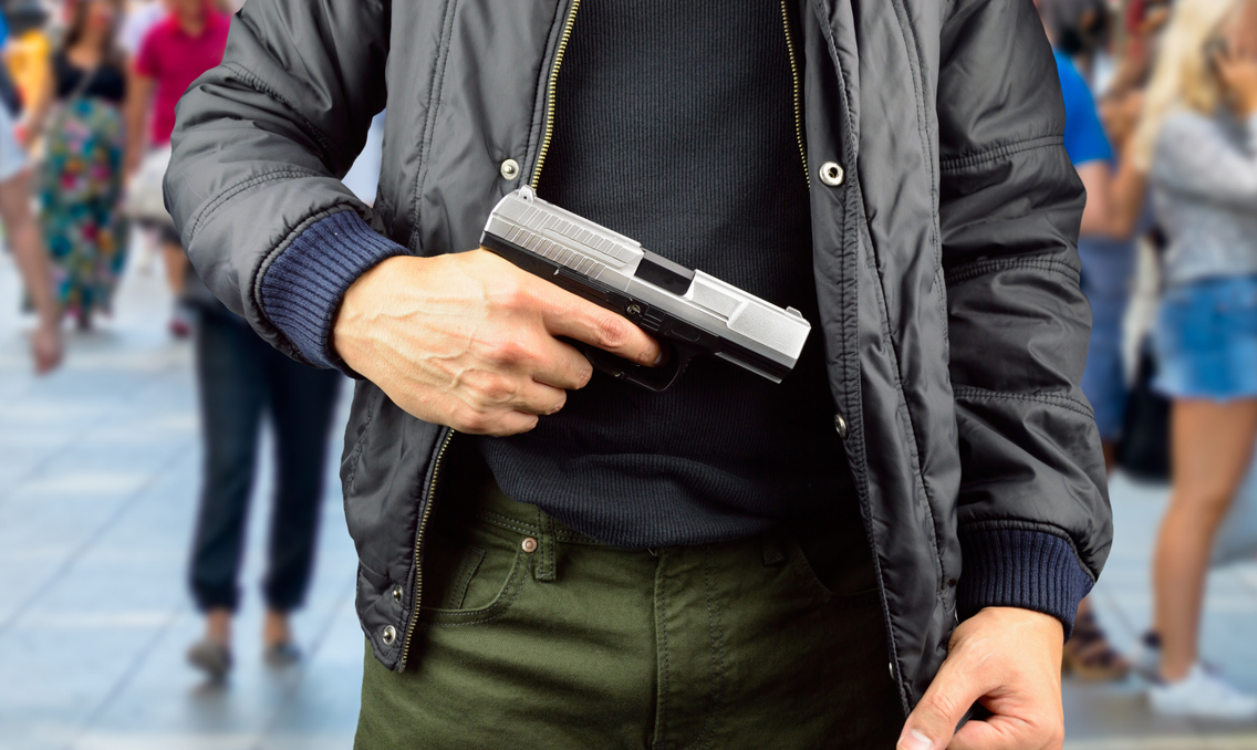 Mann holder pistol i magehøyde