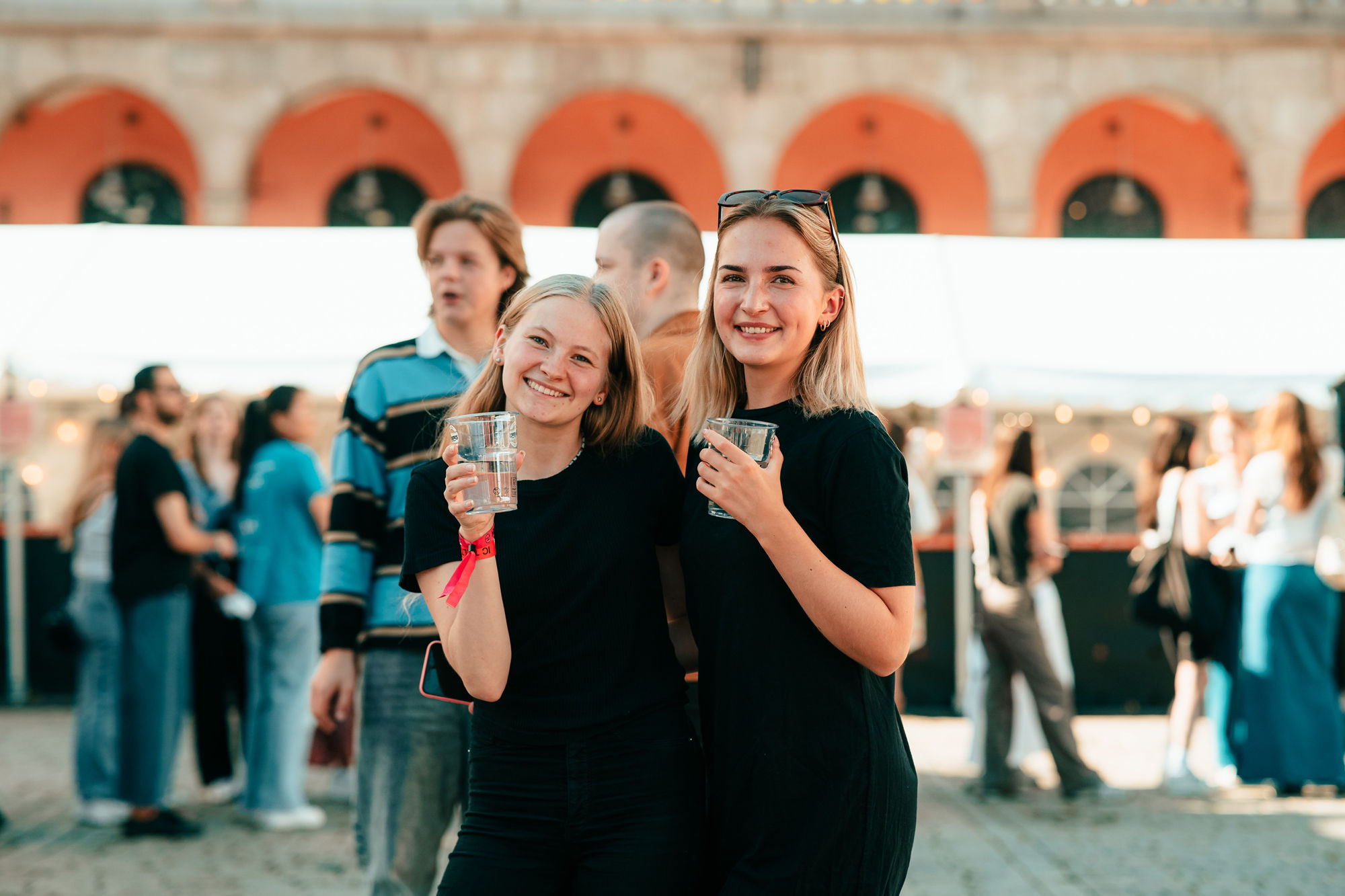Nye studenter hygger seg under fadderuka Into Campus 2023 på Youngstorget i Oslo. I forgrunnen står to unge kvinner kledd i sort. 