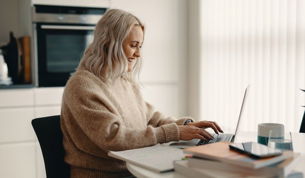 Kvinne fotografert ved skrivebord mens hun skriver på en PC