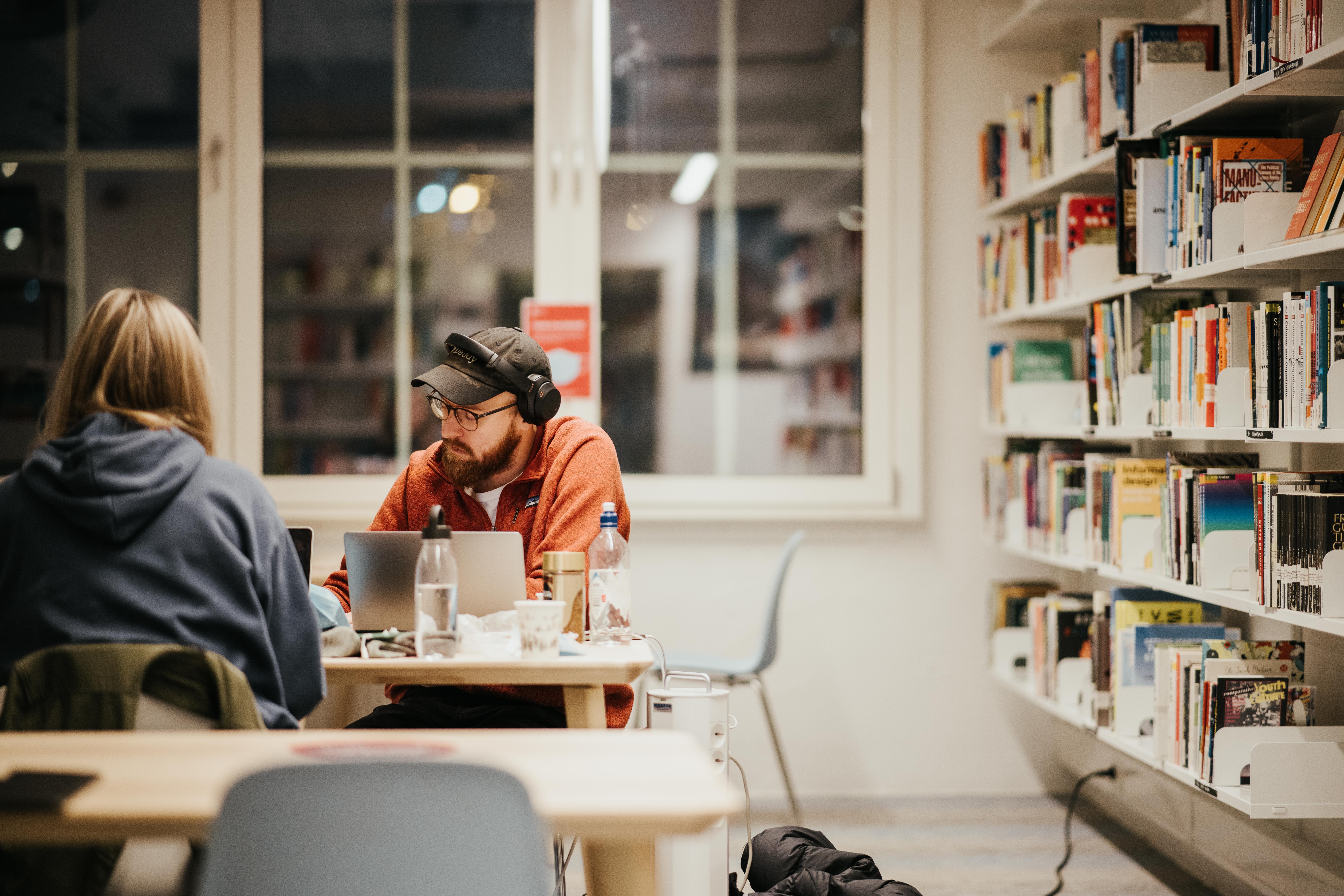 En gutt og en jente sitter på biblioteket på Fjerdingen. Gutten har rød hettegenser og ser konsentrert ut
