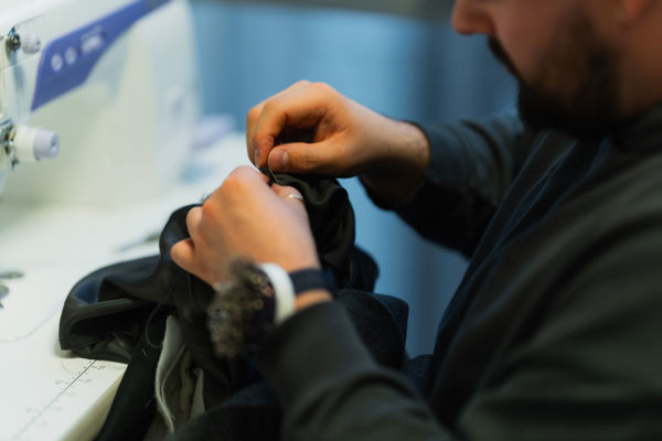 En mann bruker en symaskin til å sy sammen et plagg.