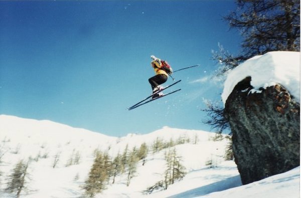 Nigel Halpern står på ski og hopper ut fra en kolle. Bildet er tatt nedenfra, og vi ser Halpern i svev mot blå himmel, over et snødekket landskap.