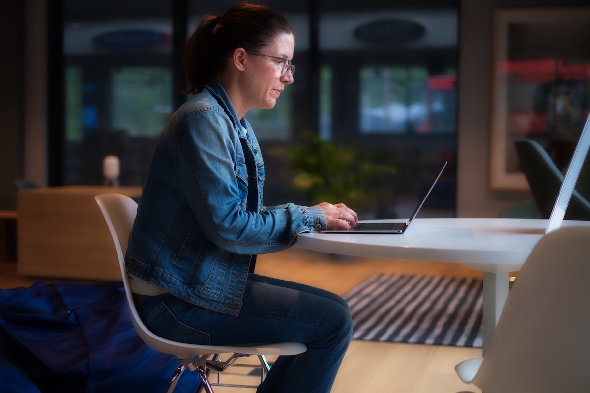 Kvinne som sitter foran en PC på et bibliotek