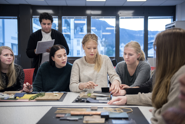 Foto av studenter ved interiørdesign som arbeider sammen rundt et bord i klasserommet. 