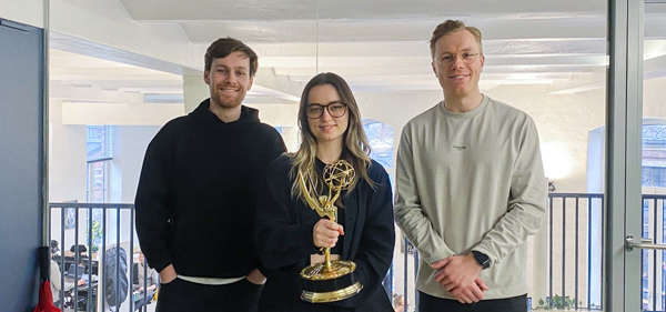 Melvin, Ingvild og Markus poserer i et kontorlandskap med en Emmy-statuett.