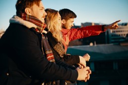 Foto av unge mennesker i varme klær som peker utover et bybilde.
