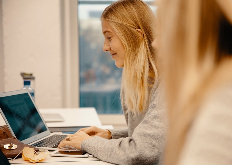 ung blond kvinne som sitter å skriver på en bærbar PC