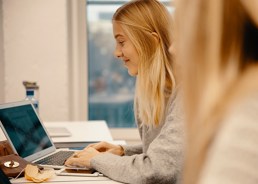 Foto av ung kvinne som skriver på en laptop.